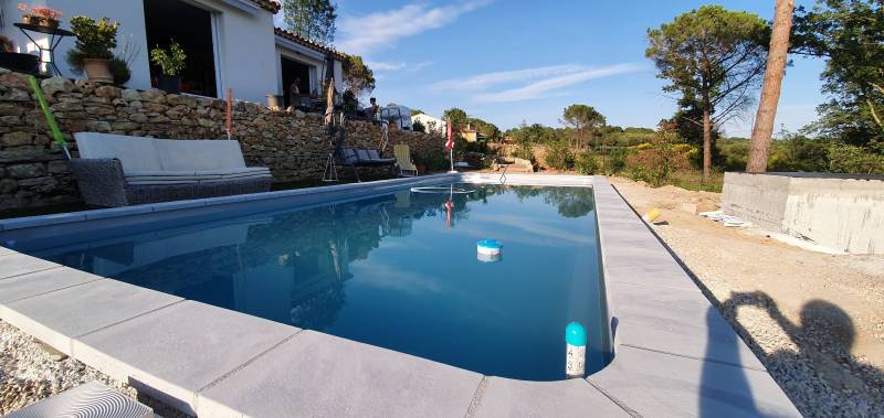 Piscine grise en coque polyester à Fréjus avec des margelles en travertin